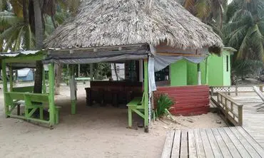 A hut with grass roof and benches on the beach.
