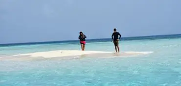 Two people walking on the beach in the water