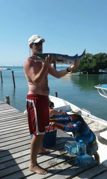 A man holding a fish while standing on the dock.