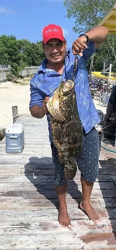 A man holding a large fish on top of a dock.