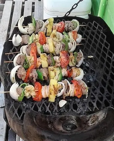 A grill with several different kabobs on it.