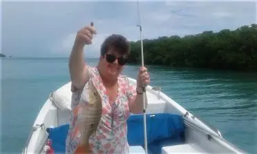 A woman holding a fish on a boat.