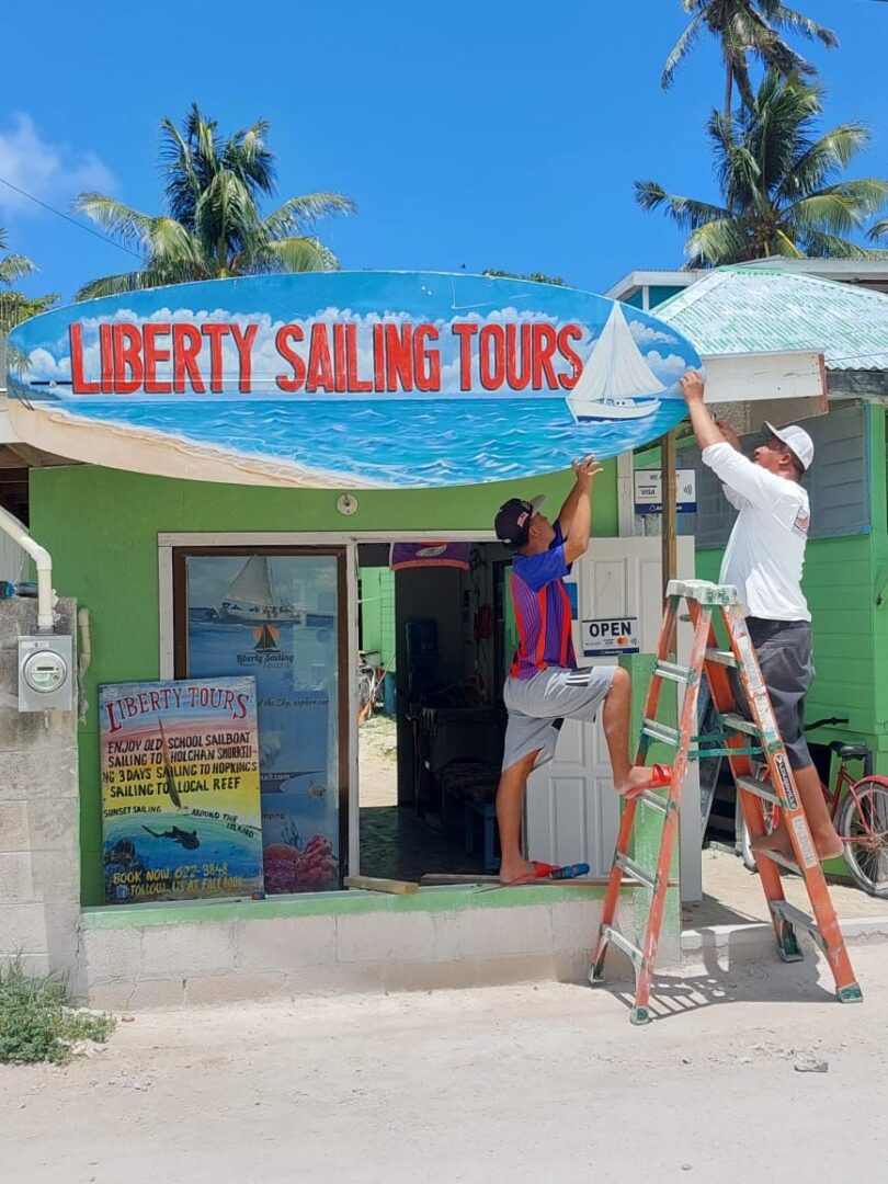 A man is hanging up the sign for liberty sailing tours.